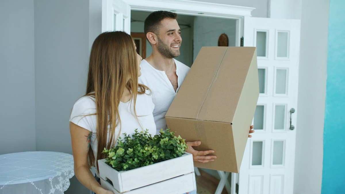 Couple carrying moving boxes into their new home